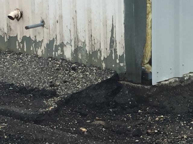   A close-up shot shows the condition of the old metal siding on the left.  Note the height of the asphalt.  The new siding is visible on the right edge of the photo